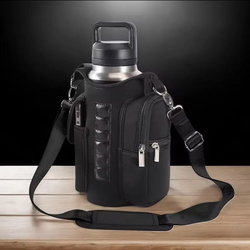 Close-up of black magnetic water bottle sling bag with dual zippers and shoulder strap, displayed on wooden surface.