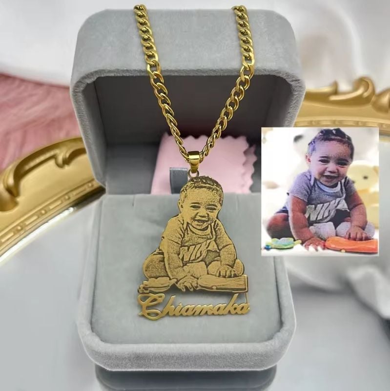 Gold custom photo necklace with baby image and Chiamaka name engraving, shown on black glove with elegant background.